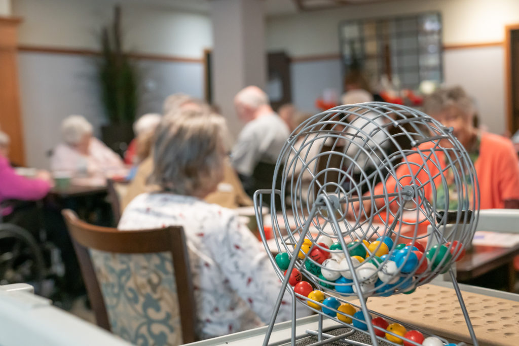 BINGO game balls in a BINGO ball spinner sits on a table in a room of seniors playing BINGO before COVID-19 required implementation of social distancing and visit restriction.